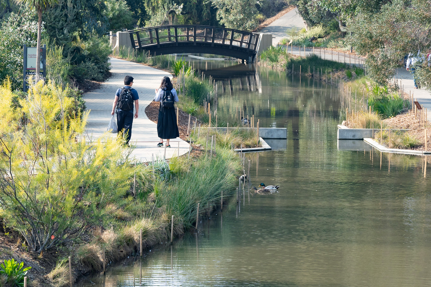 Two people walk next to the Arboretum Waterway