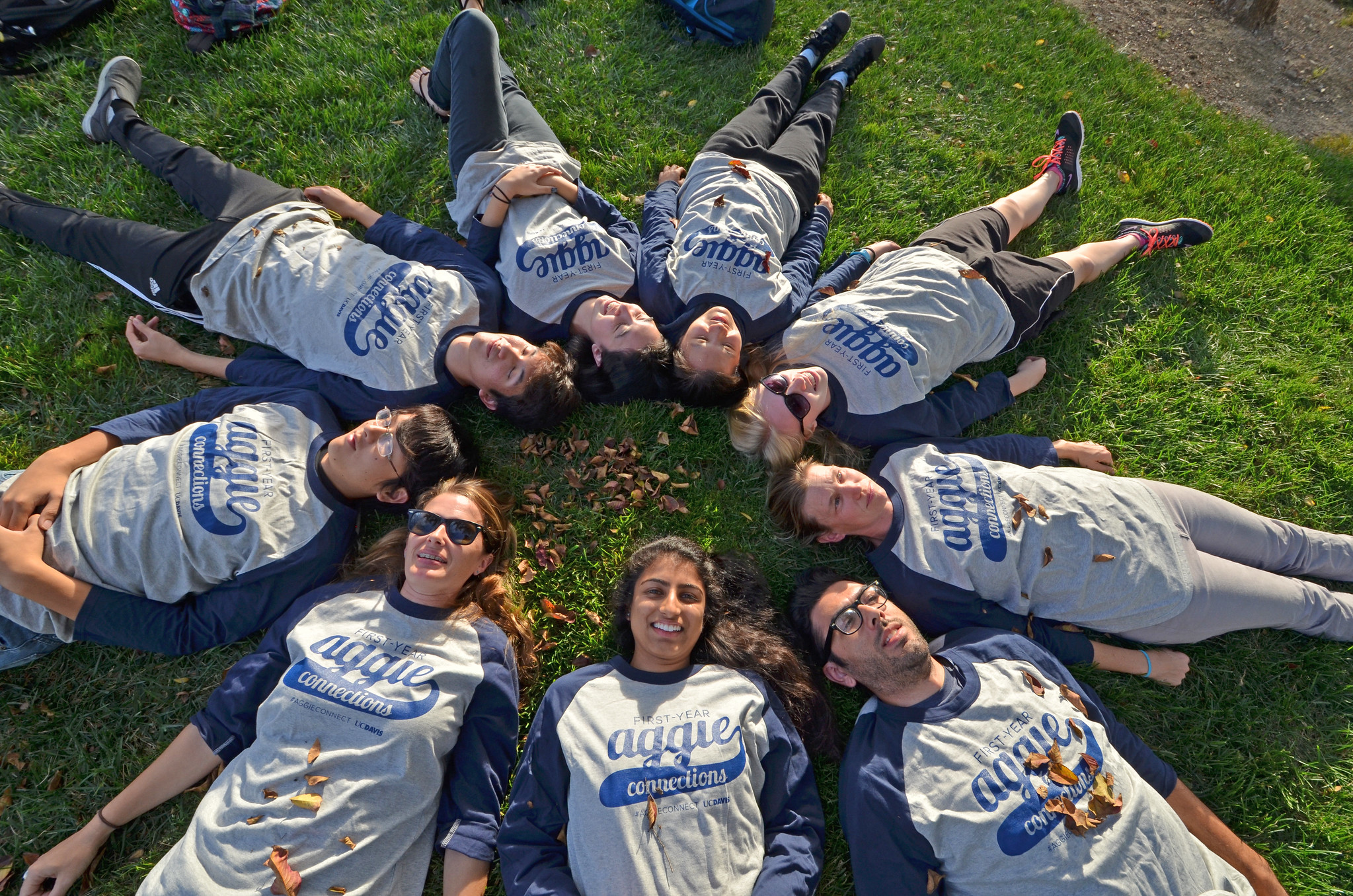 Image of students laying on the grass in a circle.