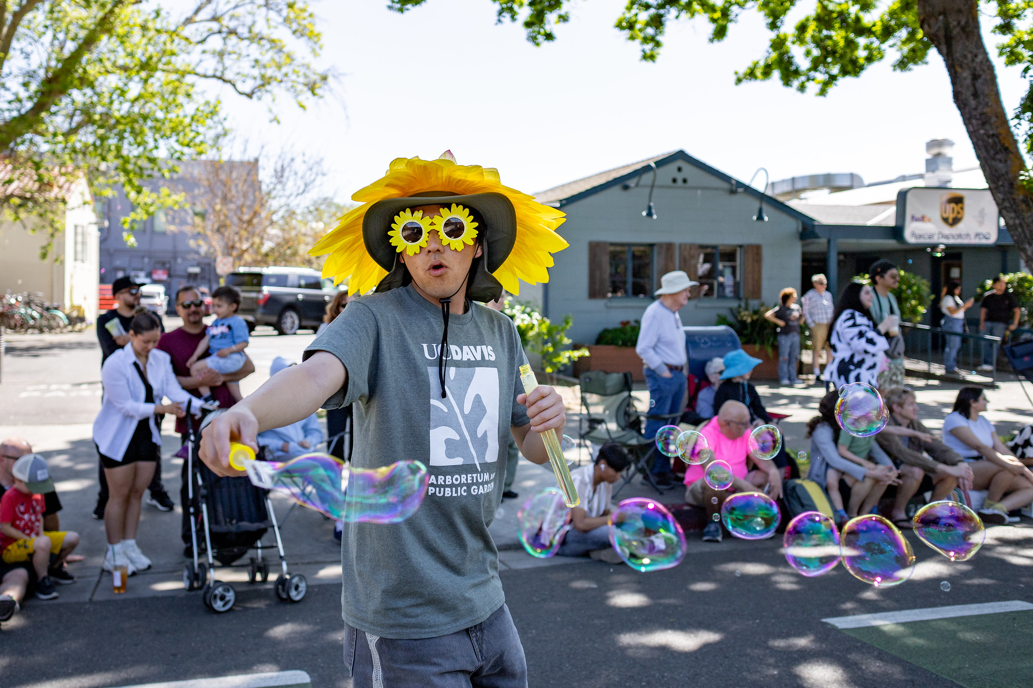 Toa Horikoshi wears a sunflower hat and sunflower glasses while using a bubble wand during the 2024 Picnic Day parade
