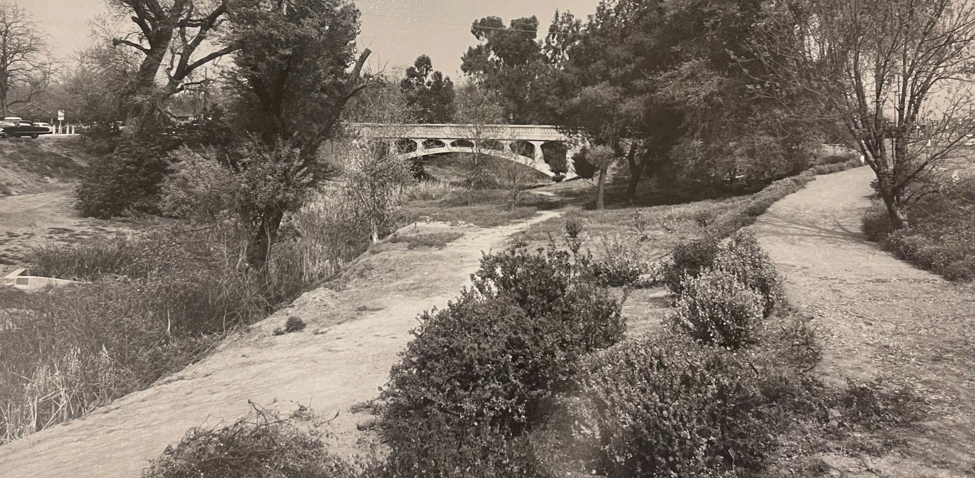 Black and white image of old A Street bridge circa 1950s or 60s. The image of shows the waterway when it was seasonally dry.