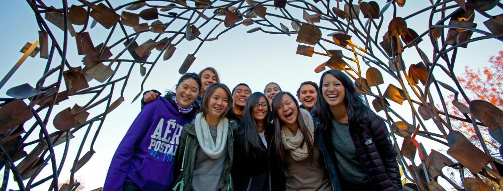 Image of students underneath the shovel sculpture located in the Arboretum GATEway Garden