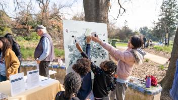 A student helps a group of children with an oak tree themed activity in Shields Oak Grove