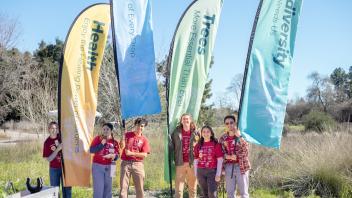 Learning by Leading student interns pose with banner flags at Biodiversity Museum Day