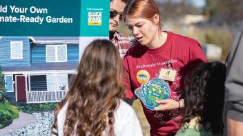 Visitors gather around the interactive "Build Your Own Climate-Ready Garden" activity at Biodiversity Museum Day