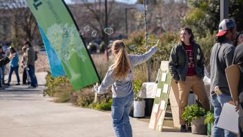 Child makes bubbles among Arboretum and Public Garden exhibits at Biodiversity Museum Day