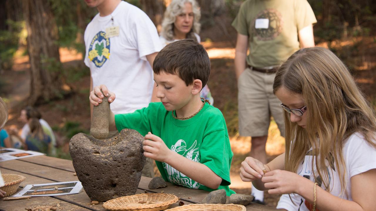 Image of young man learning how to grind acorns.