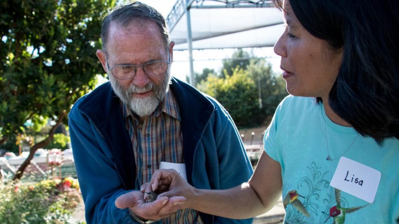 Our Arboretum Teaching Nursery is home to one of avian veterinarian Dr. Lisa Tell’s hummingbird research stations. Here Dr. Tell assists community member Donald Stoye in releasing a hummingbird after its health exam. Dr. Lisa Tell with community member Donald Stoye