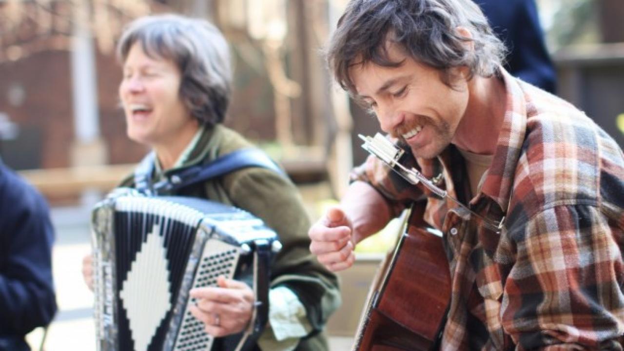 Folk musicians play instruments and laugh