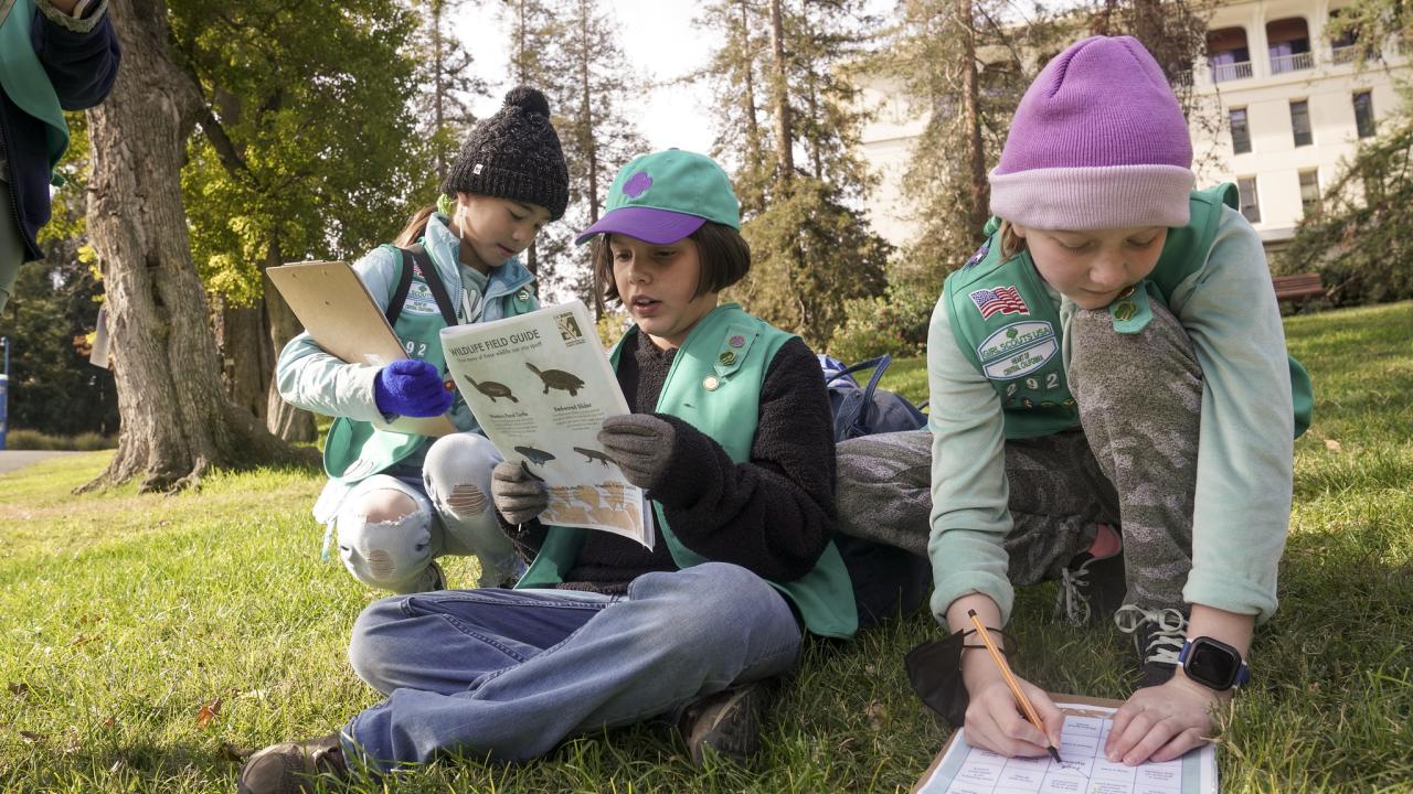 Three girl scouts fill out a Healthy Outside activity sheet