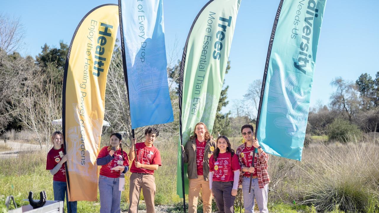 Learning by Leading student interns pose with banner flags at Biodiversity Museum Day