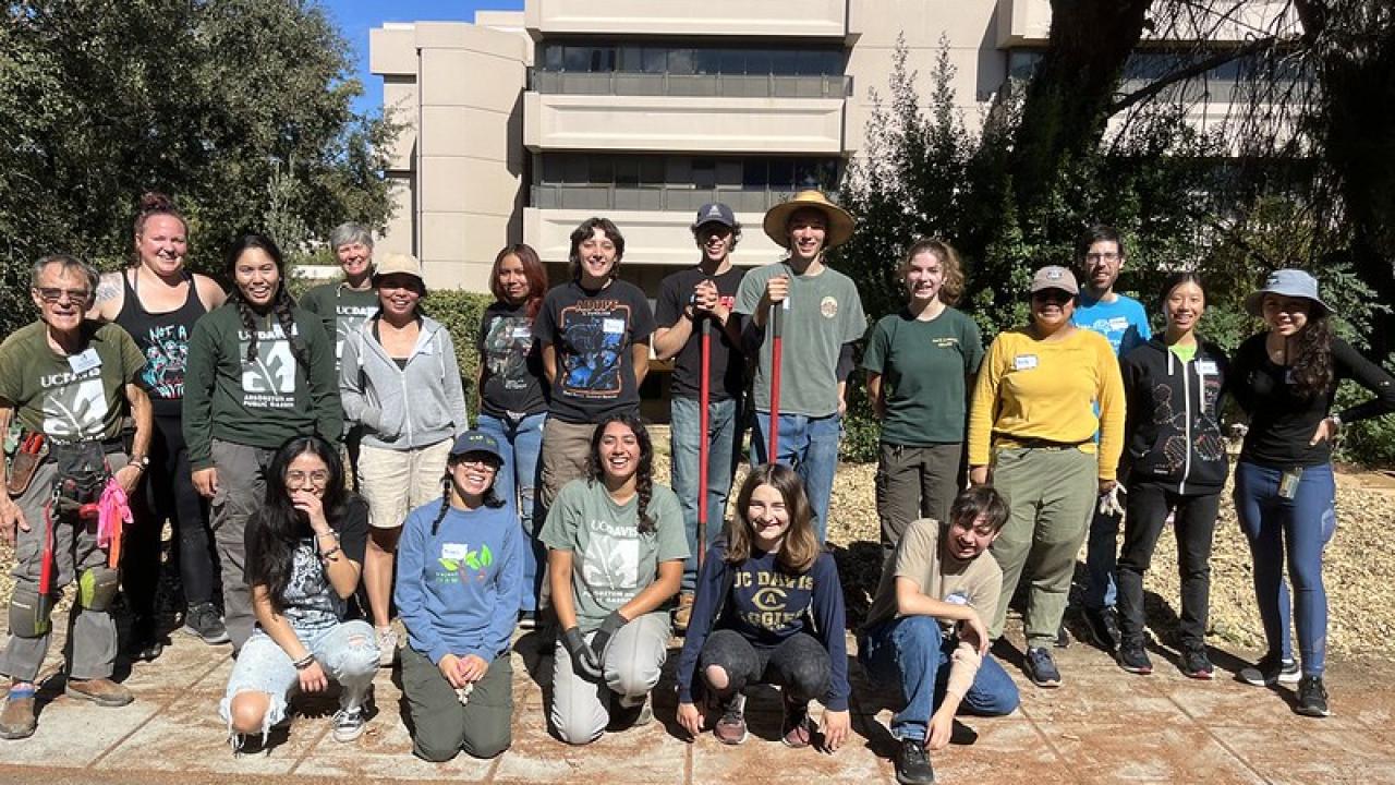 Image of diverse group of people posing outside after a day of cleaning up a garden. 