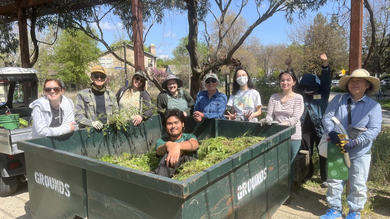 Volunteers pose with a bin full of pulled weeds in the Arboretum GATEway Garden