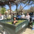 Volunteers pose with a bin full of pulled weeds in the Arboretum GATEway Garden