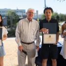 Three student interns hold certificates and pose with Brett Hewitt