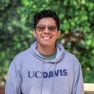 Marvin smiles, wearing a UC Davis hoodie, with leaves in the background