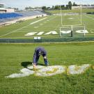 Groundskeeper paints "Go Ags" on grass near the UC Davis football field