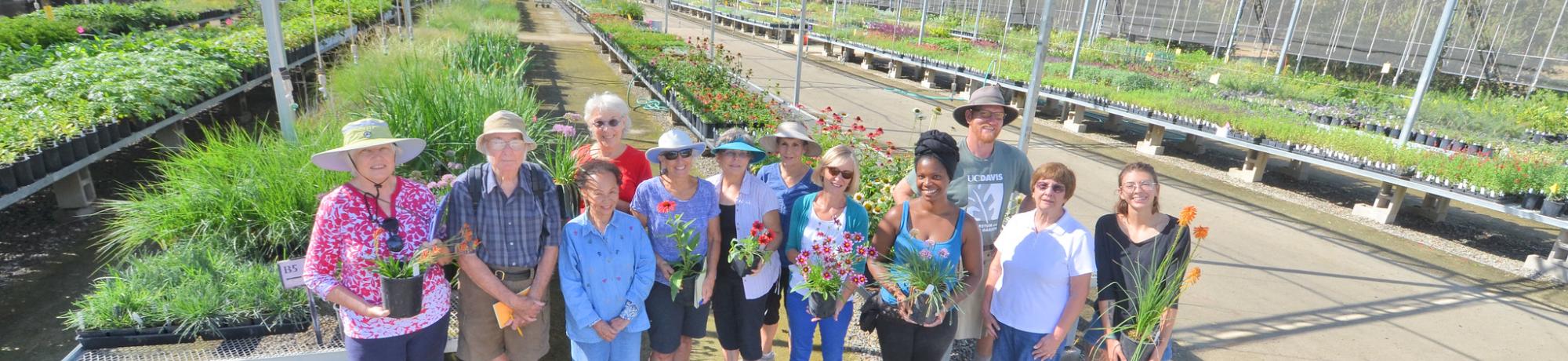 Image of students, staff and volunteers posing with plants in the UC Davis Arboretum Teaching Nursery.